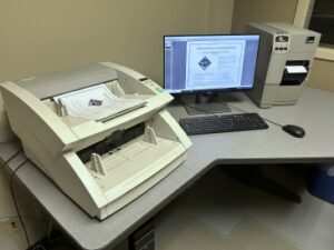 Industrial scanning machine, widescreen monitor showing scanned document, and large computer tower